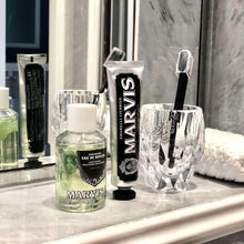 Mint mouthwash concentrate bottle with black Marvis tube and clear cup with brushes