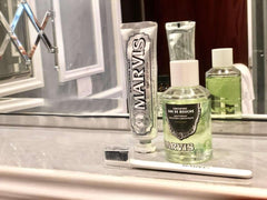 Marvis strong mint mouthwash bottle with Marvis toothpaste tube and white toothbrush on marble bathroom counter
