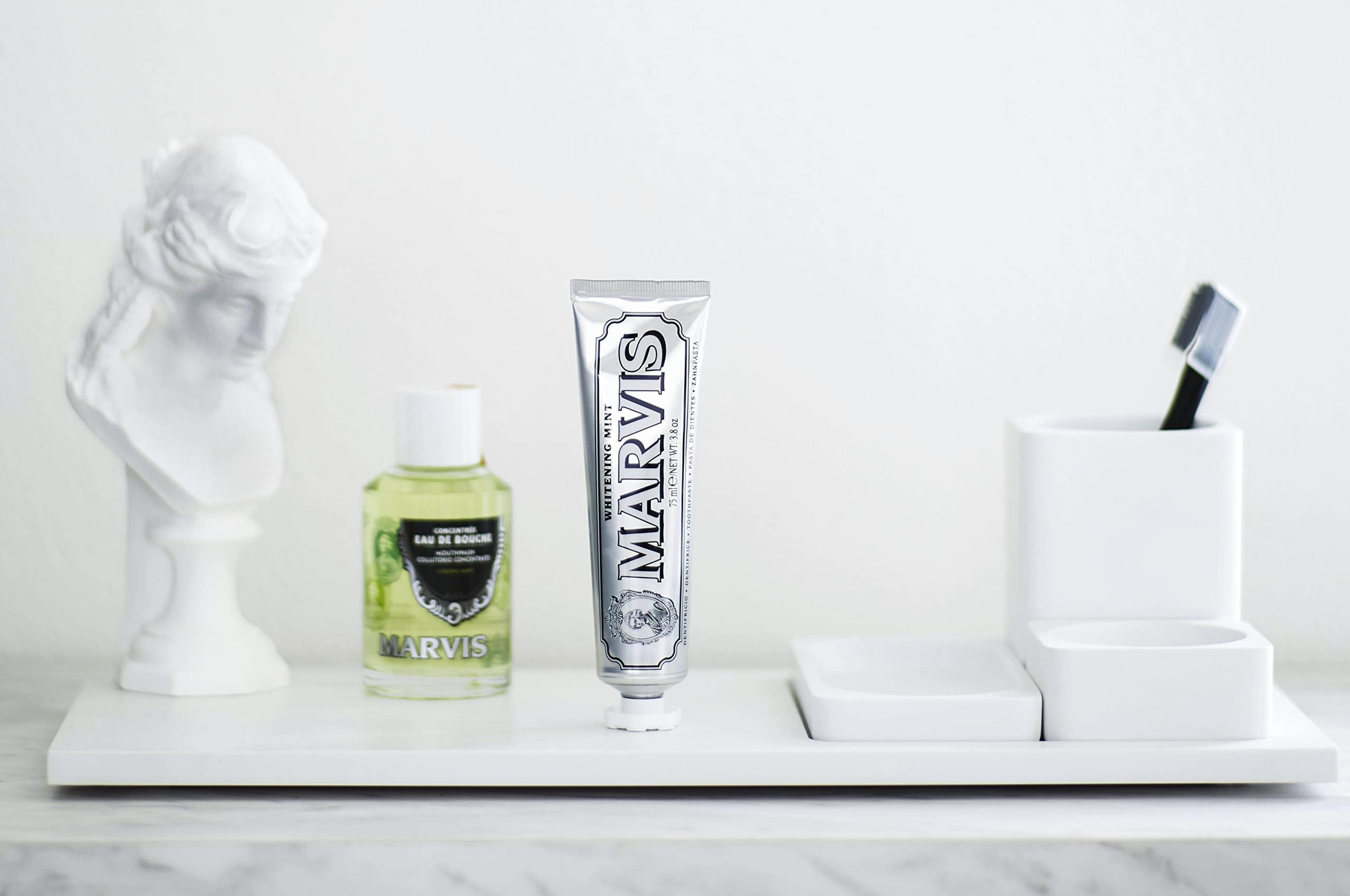 Marvis strong mint mouthwash bottle and silver Marvis toothpaste tube on white bathroom tray