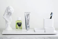 Marvis strong mint mouthwash bottle and silver Marvis toothpaste tube on white bathroom tray