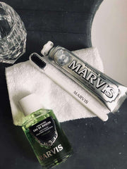Marvis strong mint mouthwash bottle with Marvis whitening toothpaste and toothbrush on towel