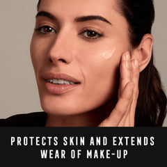 Woman applying Max Factor Miracle Prep primer SPF 30 cream on her cheek for skin protection
