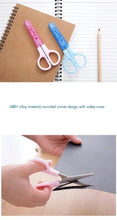Pink safety scissors with protective blade cover and rounded finger loops, in use
