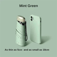Mumzar mint green mini sun umbrella pocket size next to a smartphone for scale