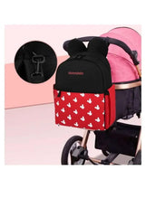 Black and red baby travel backpack with white character print attached to a stroller