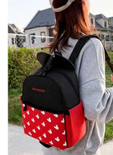 Black and red baby travel backpack with white character print, worn on back