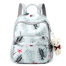Light blue diaper backpack with floral and leaf print, front zip pockets, plush keychain