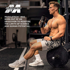 Muscletech multivitamin ad showing muscular man seated on barbell holding shaker in gym glutamine powder for muscle recovery