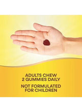 Hand holding a dark red gummy on dietary supplement packaging, adults chew 2 daily