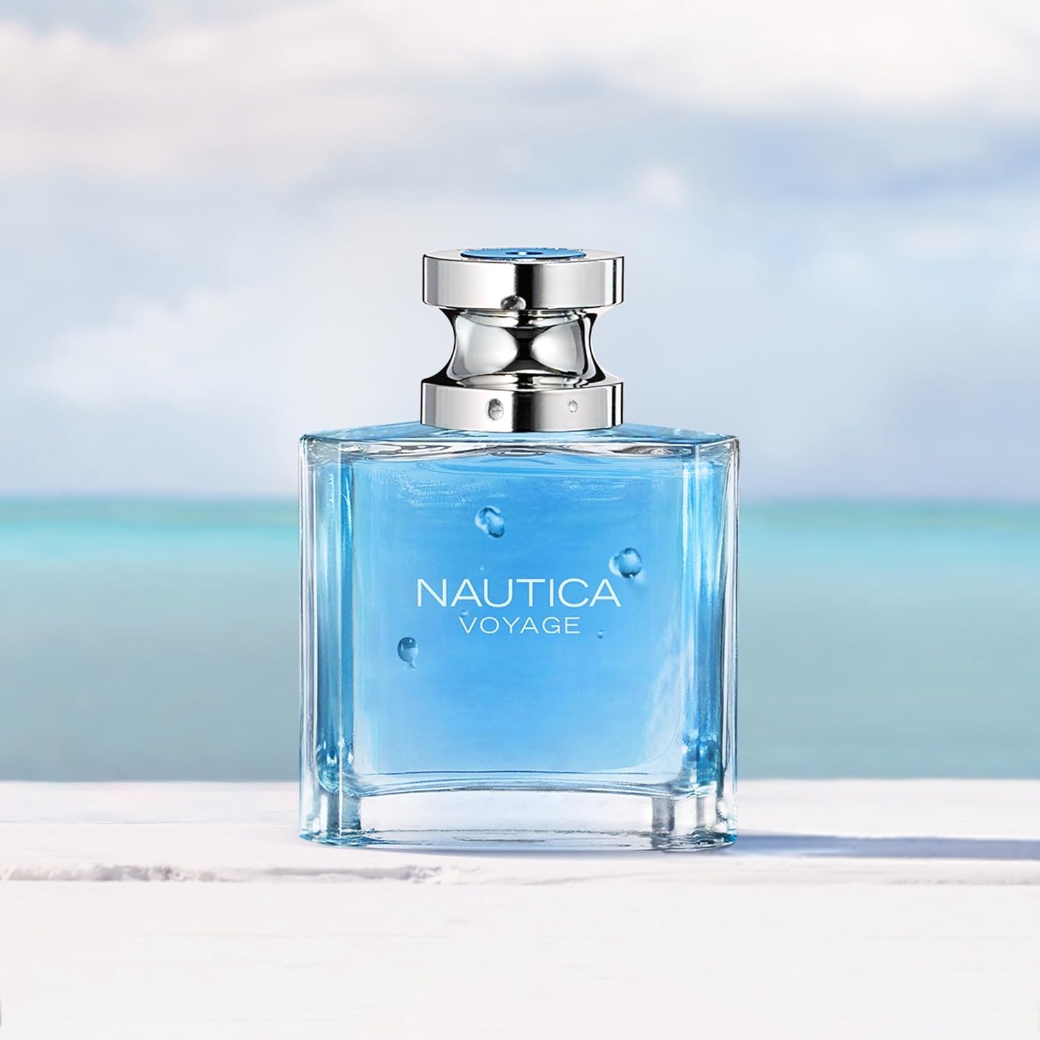 Nautica Voyage long lasting scent blue perfume bottle with silver cap on white surface by ocean