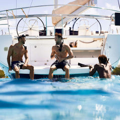 Three men enjoying a boating adventure wearing Nautica Voyage long lasting scent on a sunny day