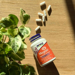 NOW Magtein supplement bottle and spilled capsules on wooden table near plant Magtein magnesium capsules UAE