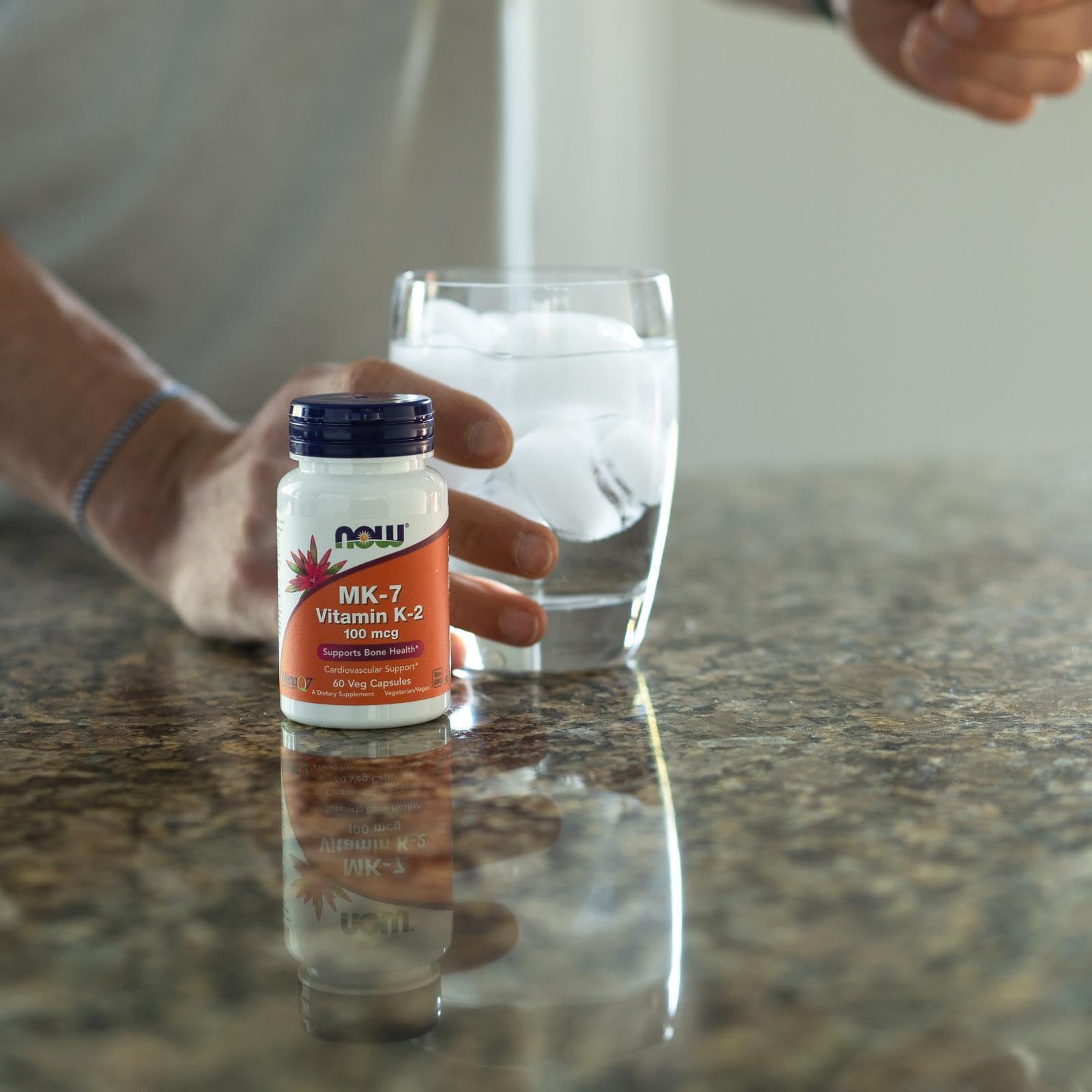 NOW Foods MK-7 Vitamin K2 supplement UAE in front of a glass of water on a kitchen countertop