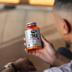 NOW ZMA supplement for sports recovery bottle held by athlete showing orange capsules and label