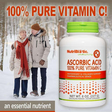 NutriBiotic Ascorbic Acid Vitamin C powder bottle beside winter shoppers, green cap, white label.