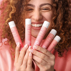 Nutrili marine collagen shots for hair skin and nails held by smiling woman in pink tubes