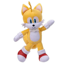 Yellow and white plush cat-like character with blue eyes, red shoes, and waving pose.