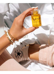Hand holding Olaplex No.7 Bonding Oil 30ml bottle with casual outfit and accessories