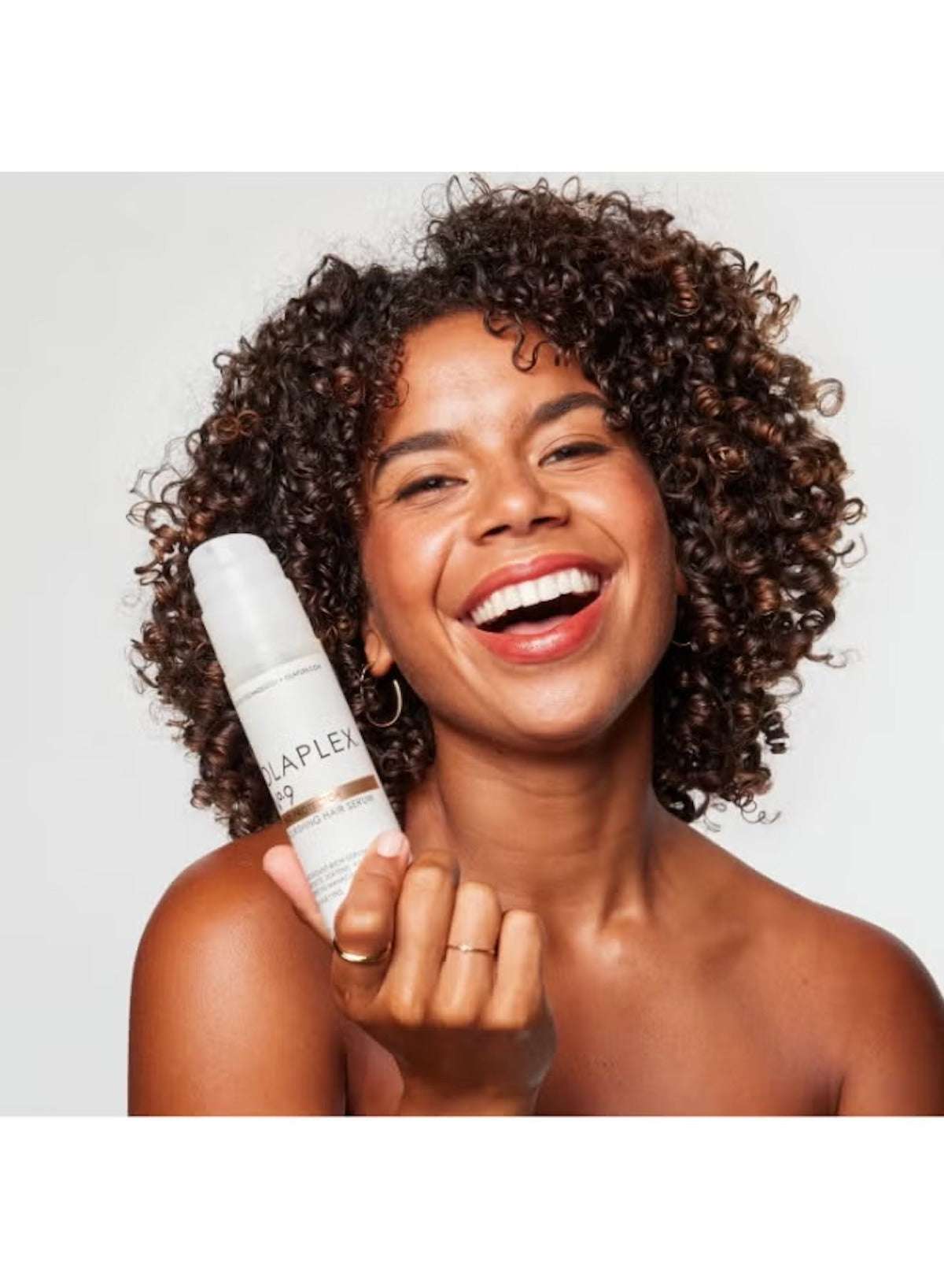 Olaplex No.9 Bond Protector Serum held by a woman with curly hair, promoting hair health and shine