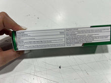 Hand holding a toothpaste carton back with Drug Facts label panel