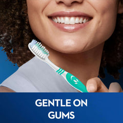 Oral-B Classic toothbrush medium held by smiling woman showing brush head and Gentle on Gums label