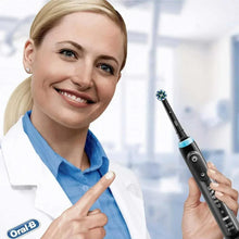 Black electric toothbrush in hand with blue collar and rotating brush head