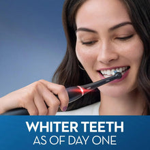 Black electric toothbrush brushing teeth held by smiling person