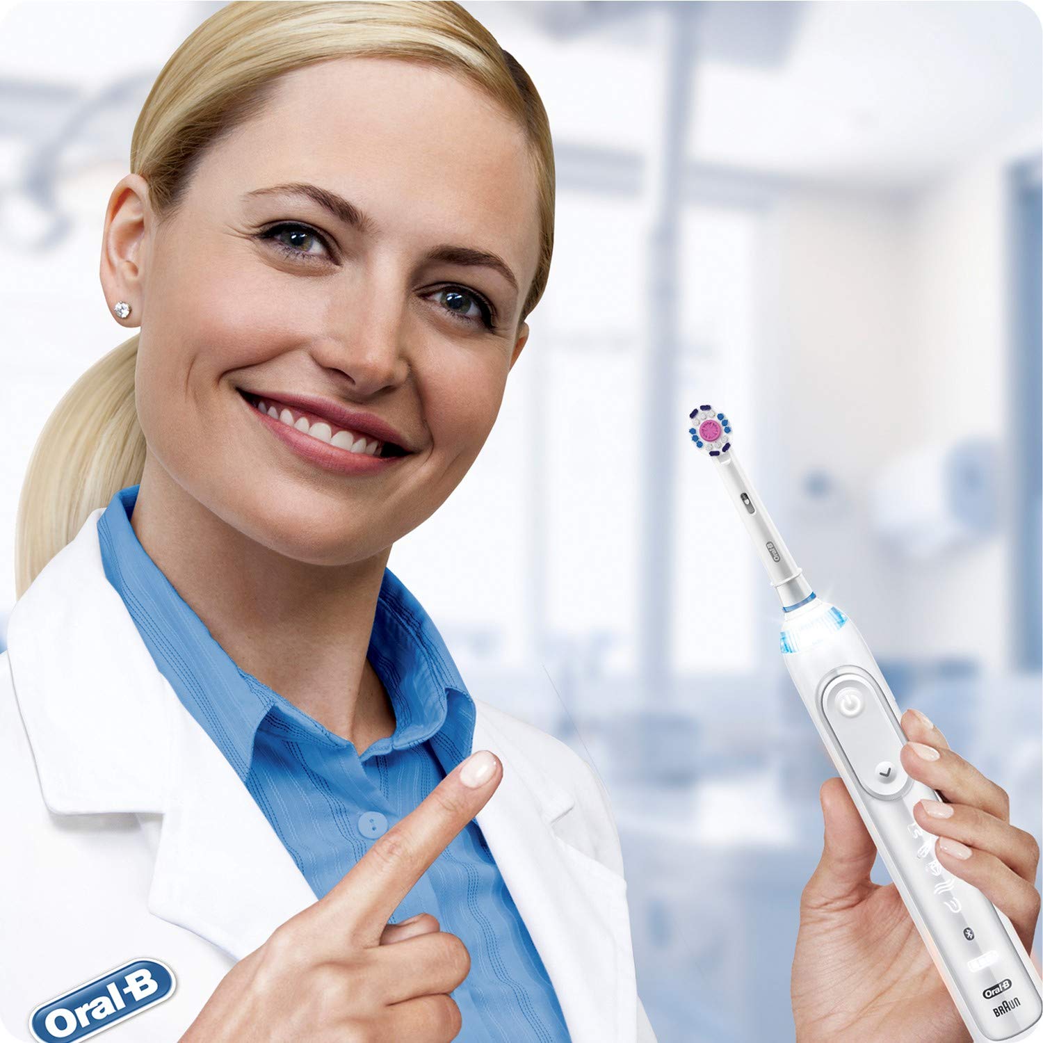 Smiling dentist in white coat pointing to an electric toothbrush fitted with Oral-B 3D White replacement brush heads.