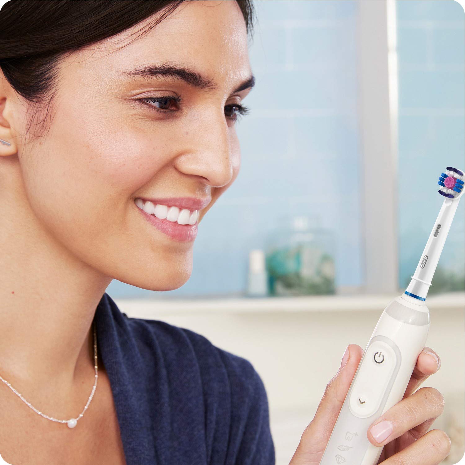Woman holding Oral-B electric toothbrush fitted with Oral-B 3D White replacement brush heads for whitening