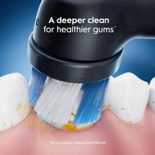 Electric toothbrush head with blue bristles on dark housing cleaning teeth