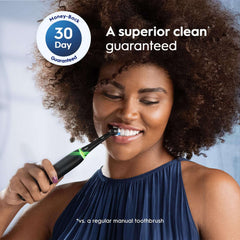 Smiling woman using a black electric toothbrush with Oral-B iO Series replacement brush heads and 30 day guarantee