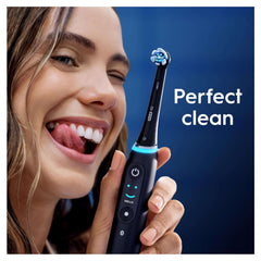 Smiling woman holding electric Oral-B iO toothbrush fitted with Oral-B iO Ultimate Clean toothbrush heads and perfect clean label