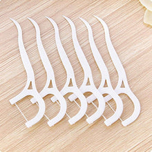Set of white plastic dental floss picks with curved handles, close-up on wood