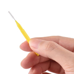 Hand holding Eacam yellow interdental brush with fine wire bristles close up on white background interdental brushes for braces