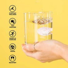 Soluble sports hydration tablet dissolving in lemon-flavoured drink, hand holding glass