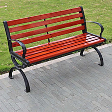 Outdoor park bench with red slatted seat and back, black metal legs on paved path