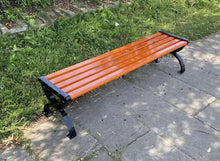 Red wooden slat bench seat with black metal legs on paved patio
