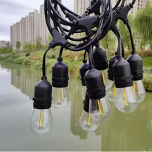 Outdoor string lights line with black sockets and clear bulbs, warm filaments visible