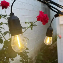 Outdoor string lights with warm glowing bulbs, black caps and clear glass bulbs