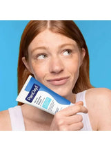 Woman holding PanOxyl acne creamy wash tube with white cream on her skin