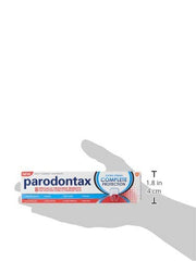 Hand holding box of Parodontax toothpaste for gum health. Complete Protection white blue packaging.