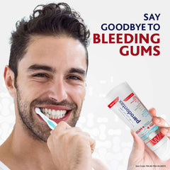Smiling man brushing his teeth while holding Parodontax toothpaste for gum problems tube to prevent bleeding gums