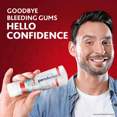Smiling man holding Parodontax toothpaste for gum problems tube against red background promoting healthy gums