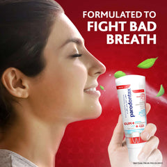 Smiling woman holding Parodontax toothpaste for gum problems tube with mint leaves and fresh breath claim