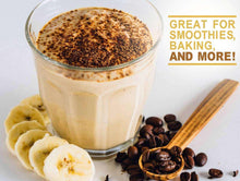 PB2 smoothie in a glass with banana slices and ground peanut powder beside.