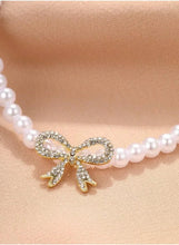 Pearl necklace with rhinestone bow pendant detail at center