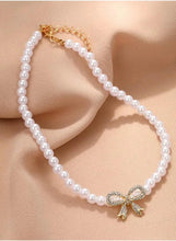 Pearl necklace with bow pendant and gold-tone chain detail at clasp