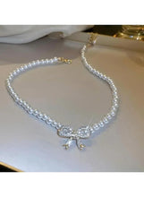 Pearl necklace with bow pendant and rhinestone accents, shown laid flat