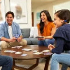 Family playing dice and gaming dice by Huitich with Phase 10 rules and instructions around a wooden table