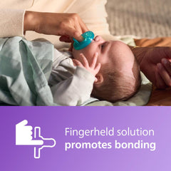 Parent placing green Philips Avent Soothie pacifier 0-3 months into relaxed newborns mouth to soothe and bond